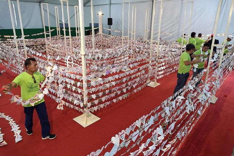 Volunteers for charity Jamiyah Singapore creating a chain of 8,525 paper hearts yesterday in a bid to set a Guinness World Record for the Longest Chain of Paper Hearts. The chain was assessed at a carnival in celebration of the charity's 85th anniver