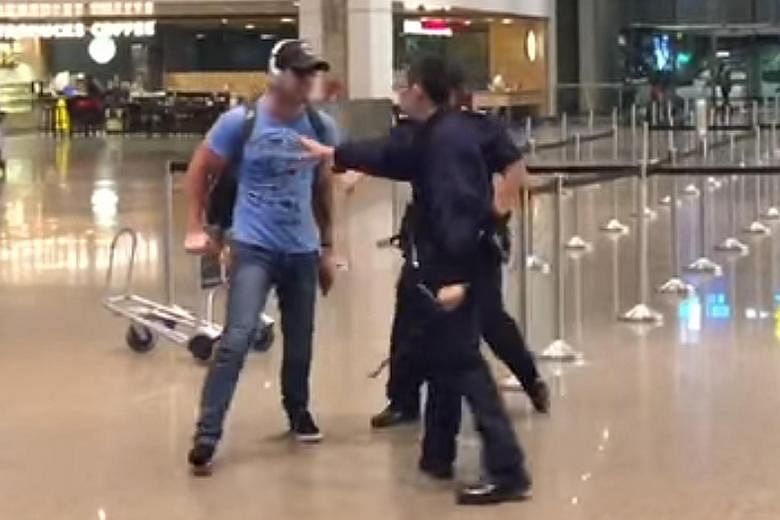 A screenshot from one of two videos showing a man, believed to be the accused, tussling with police at Changi Airport last month.