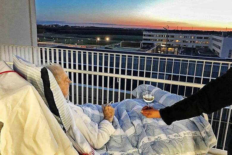 Mr Carsten Hansen watching the sunset from his hospital bed in Denmark as he enjoys a puff and a glass of white wine.