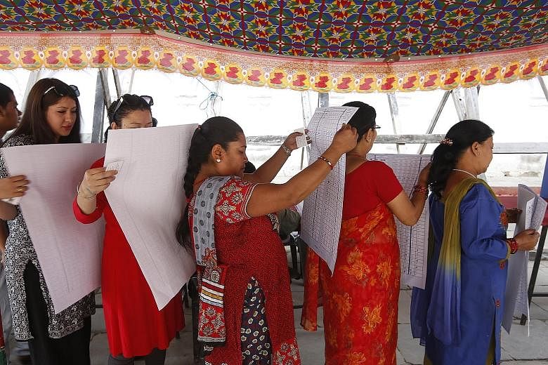 Voters at a polling station in Kathmandu's Durbar Square yesterday studying the long ballot paper with the names of the 878 candidates in the constituency. Nearly 50,000 candidates are vying for the position of mayor, deputy mayor, ward chairman and 