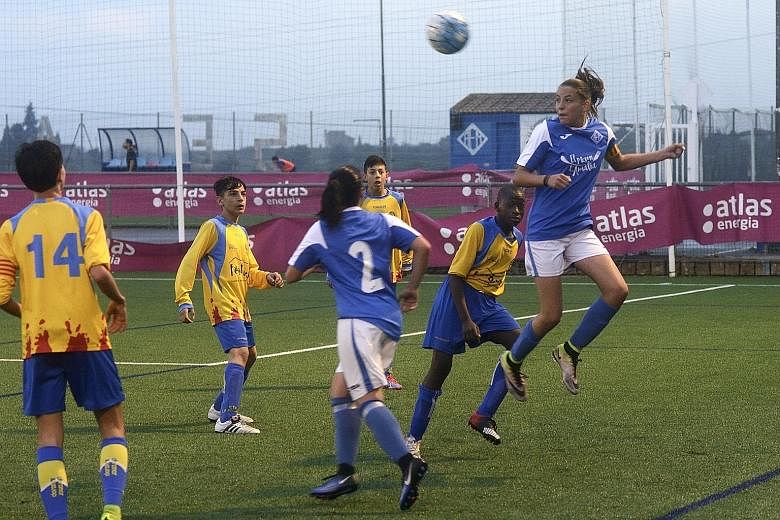 Left: The AEM Lleida girls' amateur team celebrating their league title triumph last month, as they emerged tops in a junior regional boys' league in Spain. Far left: AEM's top scorer Andrea Gomez leaping high to head the ball over the boys. She scor