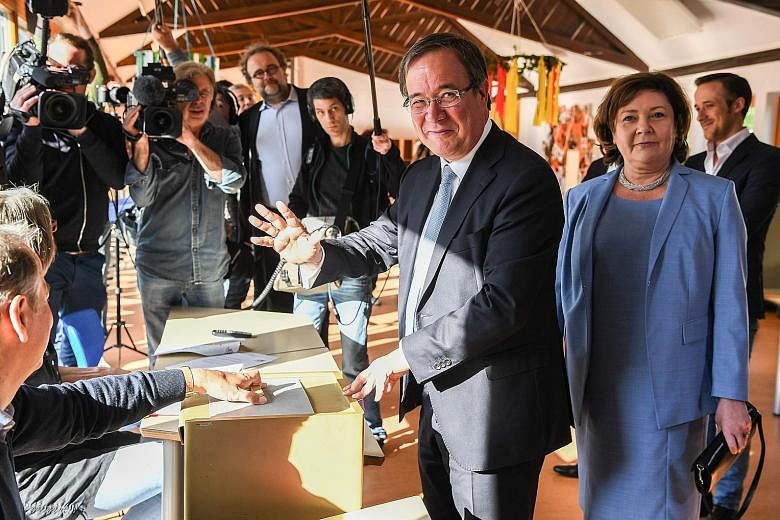 Above: Mr Armin Laschet of the CDU, with his wife Susanne, casting his ballot at a polling station in Aachen, western Germany, yesterday. Left: The SPD's Ms Hannelore Kraft, with her husband Udo and son Jan, about to cast her ballot in Muelheim an de