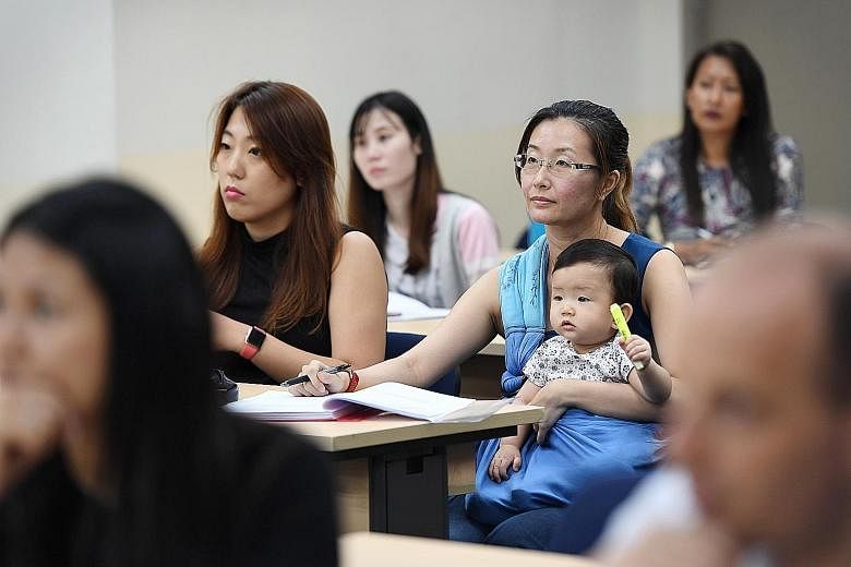 Ms Yvonne Wan with her daughter, nine-month-old Shan Ning, in class at Kaplan Higher Education Institute. Ms Wan's lecturers and classmates have been very accommodating about this unusual arrangement. Her classmates help her take notes when she needs