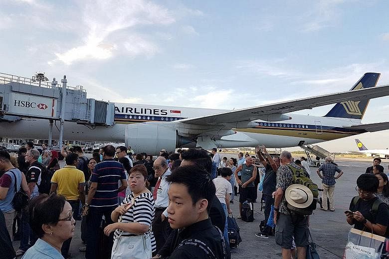 Passengers waiting on the tarmac after a fire broke out at Changi Airport Terminal 2 yesterday.