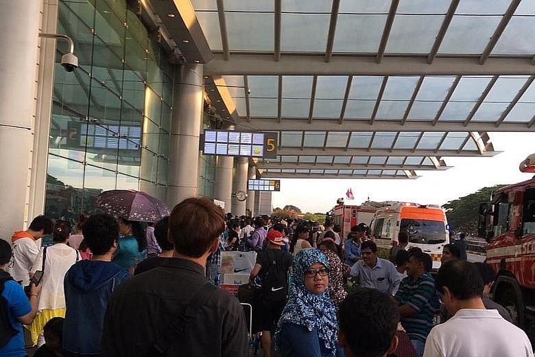 Smoke at Changi Airport Terminal 2 yesterday. Thousands of departing passengers ended up being delayed, some for more than three hours, following the fire. Passengers waiting outside Changi Airport Terminal 2. While some complained about the long wai