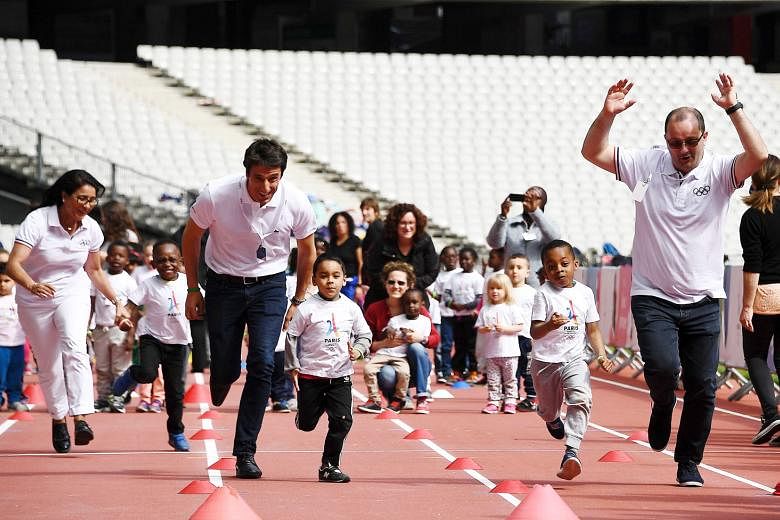 Patrick Baumann (right), head of the 2024 Olympic Games evaluation panel, and co-president of the Paris bid Tony Estanguet running with children at the Stade de France. 