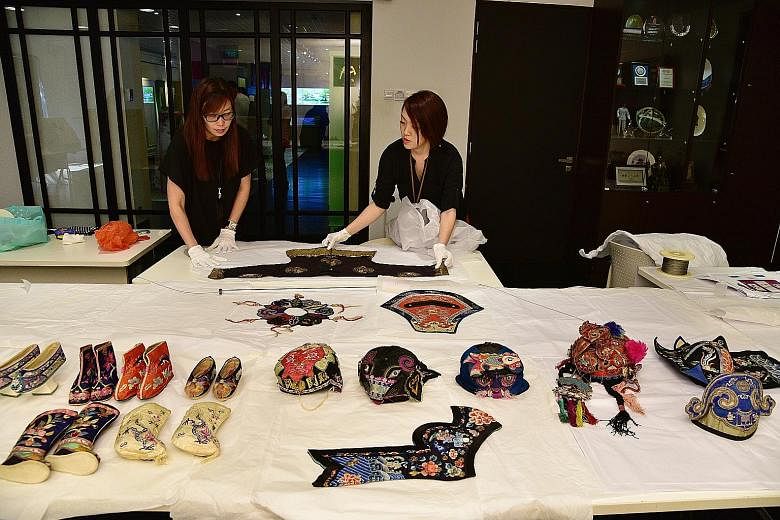 Sun Yat Sen Nanyang Memorial Hall staff preparing a boy's magua ("horse garment") from the Qing dynasty for the Stitches of Love - Hidden Blessings exhibition that opens on May 27. The magua is one of 99 artefacts that will be on display.