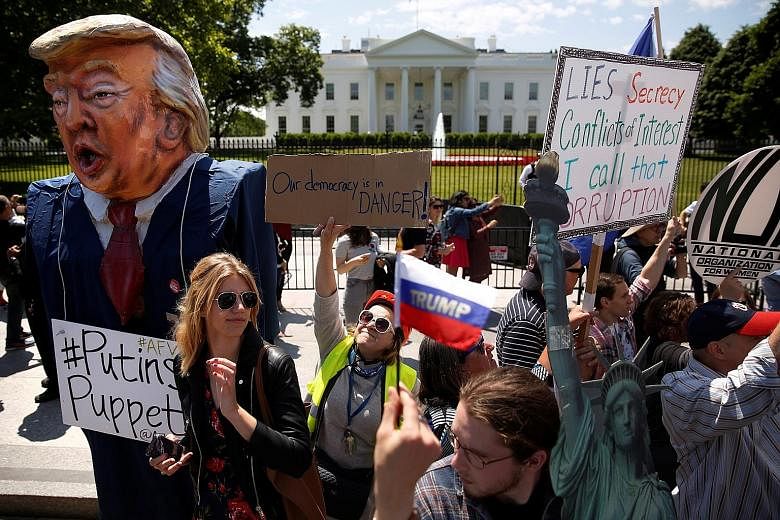 Protesters demonstrating against the firing of Mr Comey. Some believe Mr Donald Trump dismissed him primarily because of the FBI's probe into possible collusion between Mr Trump's campaign and Russian operatives. Former FBI director James Comey (left