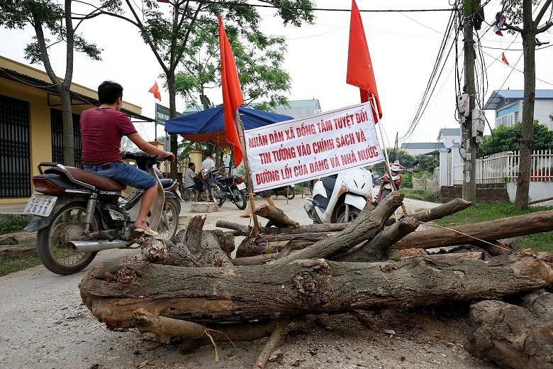 Policemen who were held hostage by Vietnamese villagers over a land dispute being released from the Dong Tam communal house, on the outskirts of Hanoi, last month. A land-dispute protest in Dong Tam on April 20. The banner reads: "The people of Dong 