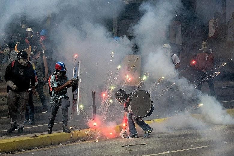 Demonstrations against the unpopular Maduro government continued on Saturday, with protesters clashing with riot police in Caracas (above) even as opposition activists blocked the city's main motorway (right). Angry Venezuelans battled on despite ons