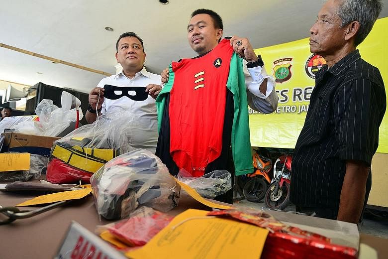 Indonesian police officers yesterday showing costumes and other evidence gathered in Sunday's raid of an alleged gay party.