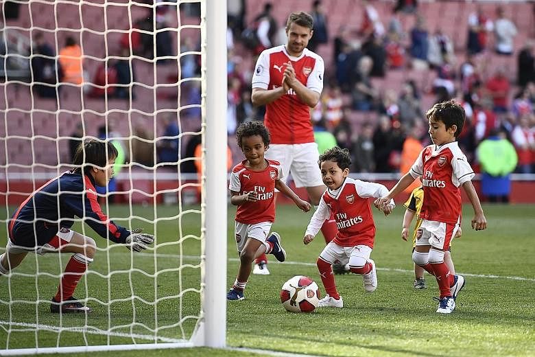 Arsenal's Aaron Ramsey watching some of his team-mates' children play on the Emirates pitch during the traditional end-of-season lap of appreciation with players and their family. The Emirates supporters will have to get used to navigating the unchar