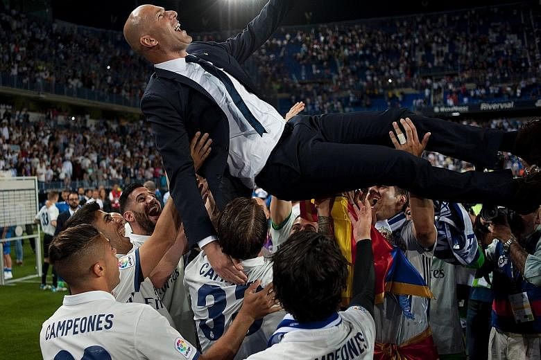 Real Madrid coach Zinedine Zidane is hoisted in the air by his players after a 2-0 win over Malaga sealed their 33rd La Liga crown, three points clear of rivals Barcelona.