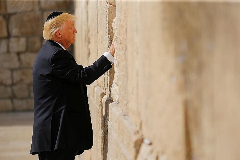 US President Donald Trump placing what seemed to be a written prayer or note between the stones of the Western Wall, the holiest site where Jews can pray, in Jerusalem's Old City yesterday. He made history by becoming the first sitting US president t