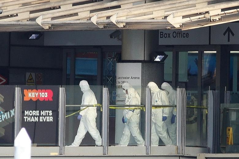 Police forensic officers walking along a bridge that links Victoria station to the Manchester Arena. The attack in the northern English city of Manchester is the worst such incident on British soil since the London bombings of 2005. Above: A woman we