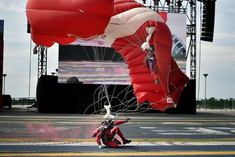 Third Warrant Officer Sim Chee Jin getting entangled in mid-air in the parachute of a teammate before landing on his side (above, right) at the F1 pit yesterday. He did not get up after the landing and had to be stretchered off. The Singapore army sa