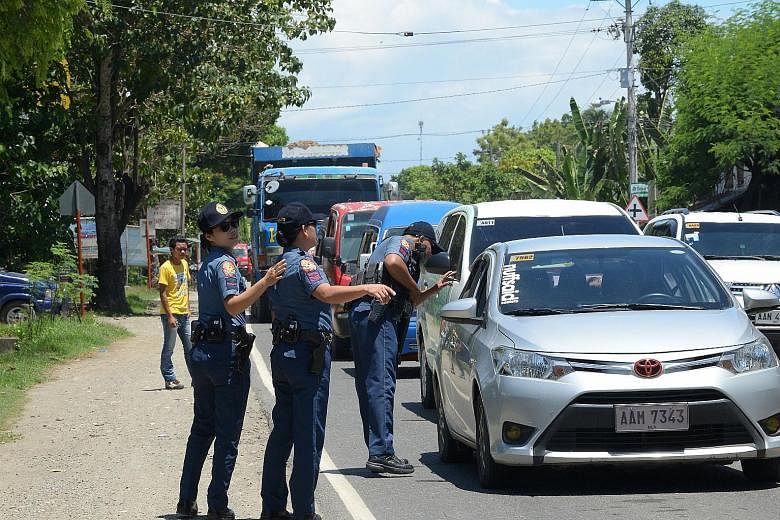 A police checkpoint set up along a highway yesterday in Iligan City, Mindanao. The southern island group of Mindanao is home to some 20 million Filipinos. Residents fleeing Marawi City yesterday after militants mounted attacks, torching buildings, be