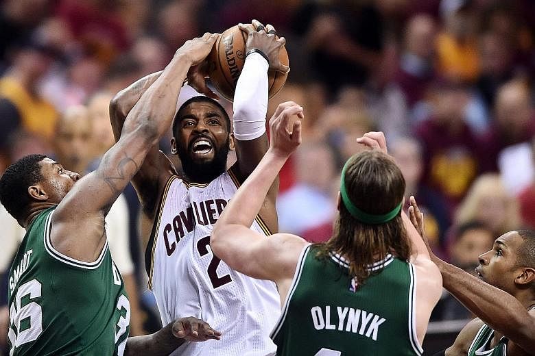 Cleveland guard Kyrie Irving driving to the basket between Boston guard Marcus Smart and centre Kelly Olynyk in Game Four. The defending NBA champions came from behind to win 112-99 and can seal their return to the Finals by taking Game Five in Bosto