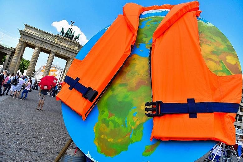A giant globe dressed with a life jacket during a protest by environmental activists from Greenpeace outside the venue of the Petersberg Climate Dialogue in Berlin on Tuesday. China, Canada and the European Union will convene a ministerial-level meet