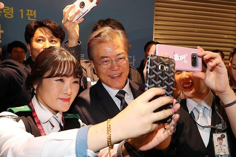 Airport employees taking selfies with Mr Moon at the Incheon International Airport in Seoul last week. Mr Moon's popularity is at a peak, with 87 per cent of respondents in a Gallup poll positive about the outlook for his performance. South Korean Pr