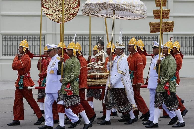 Thai officials in traditional costumes carry the statue of Buddha from Amphorn Sathan Residential Hall to a merit-making ceremony at Dusit Palace in Bangkok on Tuesday. Thousands of monks and well-wishers joined the ceremony to commemorate the late K