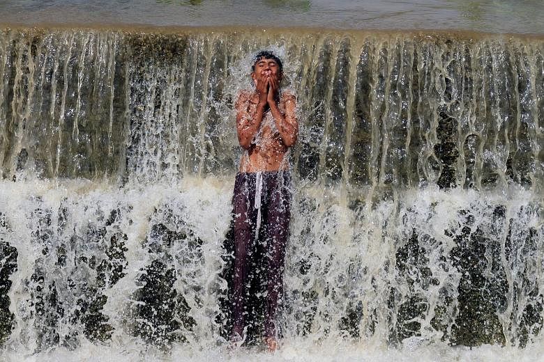 A boy bathing in a stream to cool off from the summer heat, in the city of Swabi in Pakistan on Wednesday. Intense heat has scorched parts of the country in recent days, ahead of the start of the monsoon season.
