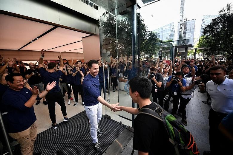 Mr Xiang Jiaxin being welcomed as Apple Orchard Road's first customer yesterday. He had queued from 8pm last Friday night.