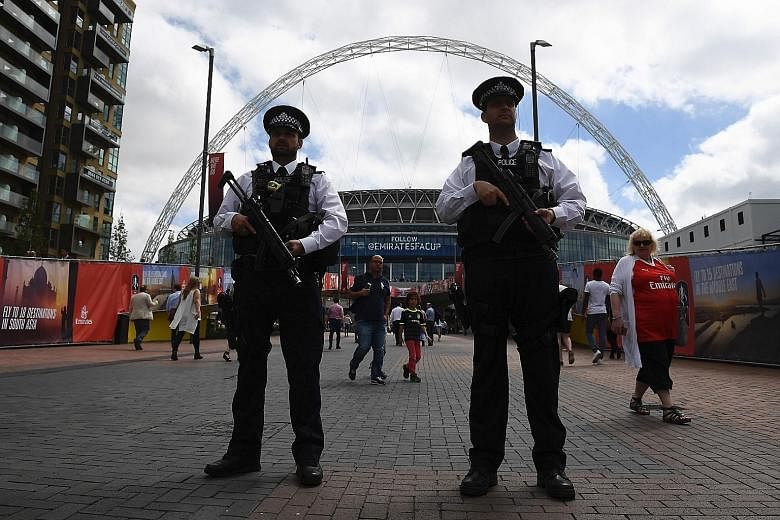 Armed police standing guard outside Wembley Stadium in London yesterday. Elsewhere in the capital, police patrols were visible at underground and rail stations and on the streets, especially in tourist areas.