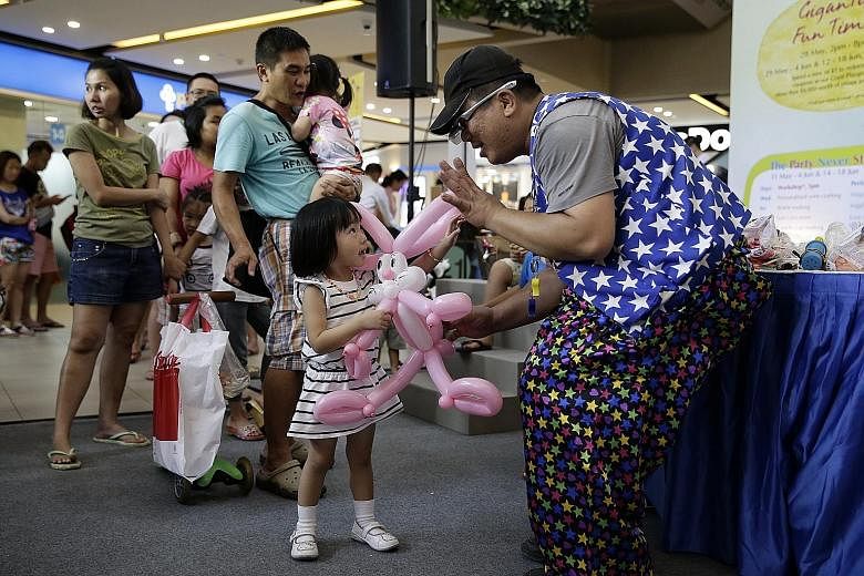 Three-year-old Gwendolyn Sim getting a balloon sculpture made by Mr Chia Meng Choon, 42, better known as Mr Lightning Fingers, yesterday at an event to celebrate The Seletar Mall's second anniversary. 	During the two-hour balloon sculpting segment of