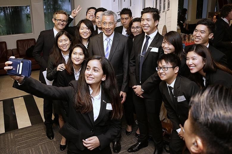 Above: Prime Minister Lee Hsien Loong receiving the book E.W. Barker: The People's Minister from Mrs Gloria Barker after the launch of the EW Barker Centre for Law and Business. Left: PM Lee and NUS law dean Simon Chesterman taking a wefie with stude