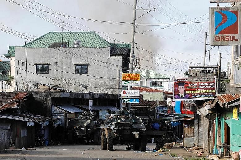 A Filipino soldier keeping a watchful eye as fighting continues between the Islamist militants and government forces in Marawi on Sunday. Above: A black ISIS flag is seen in a militant stronghold in the city yesterday. The Philippine military's spoke