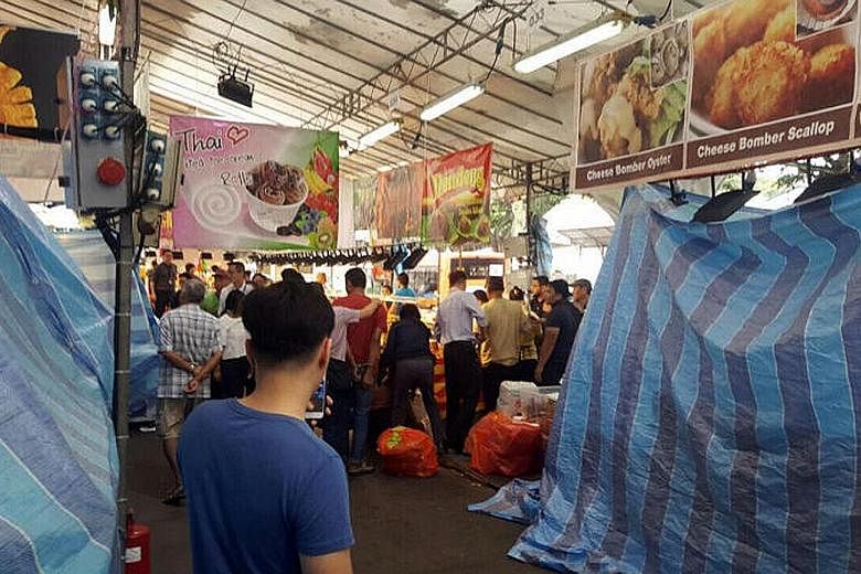 Unregistered food handlers being arrested at the Geylang Serai Bazaar during a joint operation by MOM, NEA and the police yesterday.
