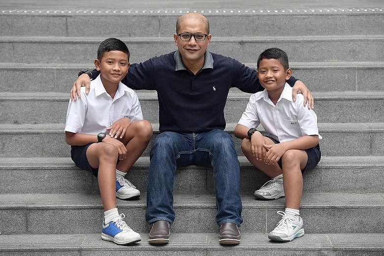 Brothers Muhammad Raihan (left), 12, and Muhammad Razin, 9, with their father, Mohd Airudin. They were among 335 student athletes who received SOF-Peter Lim scholarships yesterday. The $1,000 that the siblings each received will likely go towards the