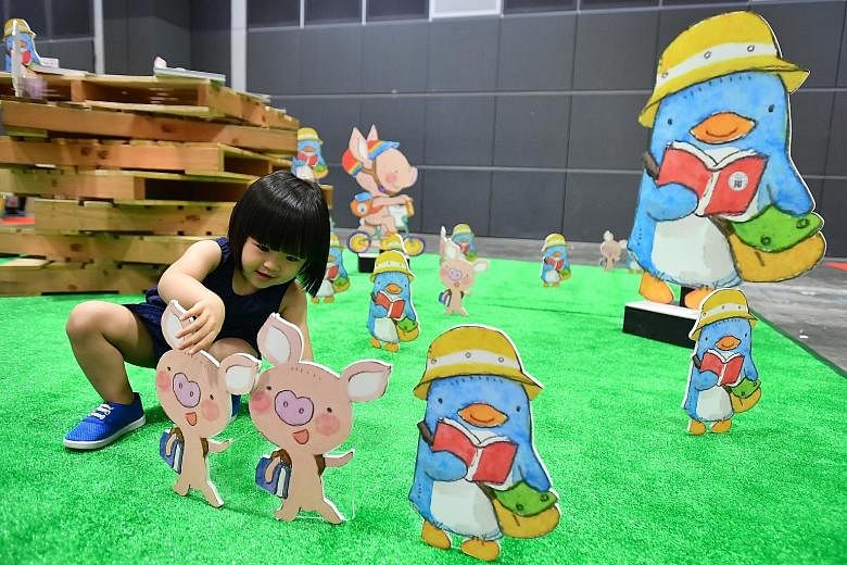 Lee Simin, two, playing with standees of characters created by local illustrator Ah Guo at the Singapore Book Fair at Suntec Singapore Convention & Exhibition Centre yesterday. The event runs till next Monday.