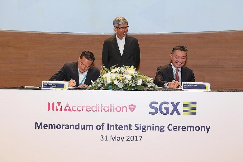 IMDA chief executive Tan Kiat How and SGX chief executive Loh Boon Chye signing a memorandum of intent to help high-tech start-ups. With them is Minister for Communications and Information Yaacob Ibrahim.