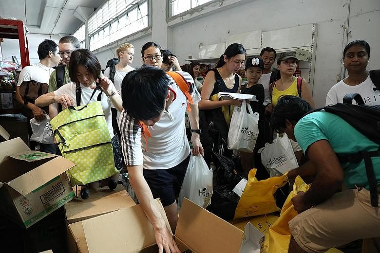 Dentsu Aegis Network staff cleaning a children's home (top) and packing food bundles at Food Bank (above) that were delivered to Thye Hua Kwan Family Services Centres, as part of the company's "One Day for Change" initiative on May 19.