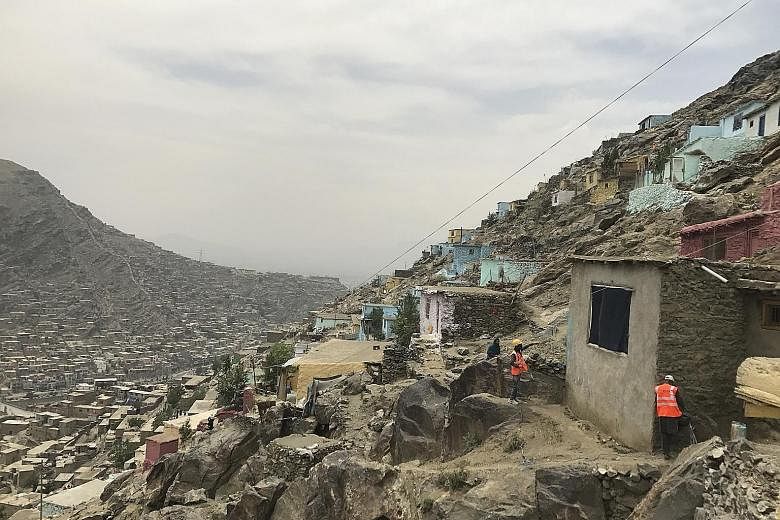 Painters adding colour to the front of a hillside home in Kabul. While many residents have been supportive of the effort, some activists feel it is better to focus on paving paths to the homes high up the mountains or providing water to houses whose 