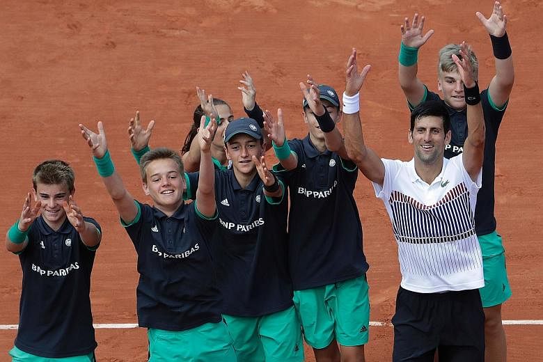 Novak Djokovic celebrating with the ball boys after his second-round French Open win. He will next play Diego Schwartzman.