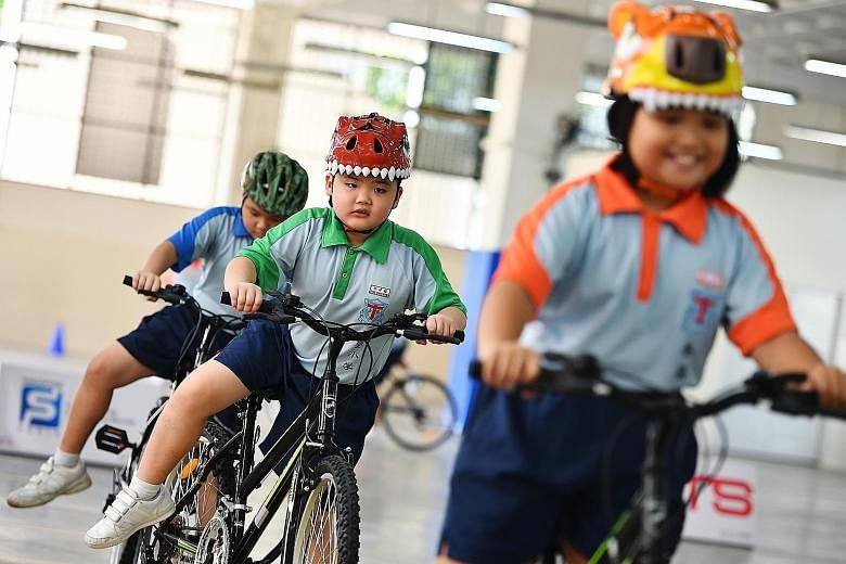 Primary 2 pupil Tang Xiang Rong (centre), eight, is one of 21 pupils from Holy Innocents' Primary School taking part in the two-day Singapore Cycle Safe programme, launched yesterday. It also aims to combat childhood obesity. To make the learning fun