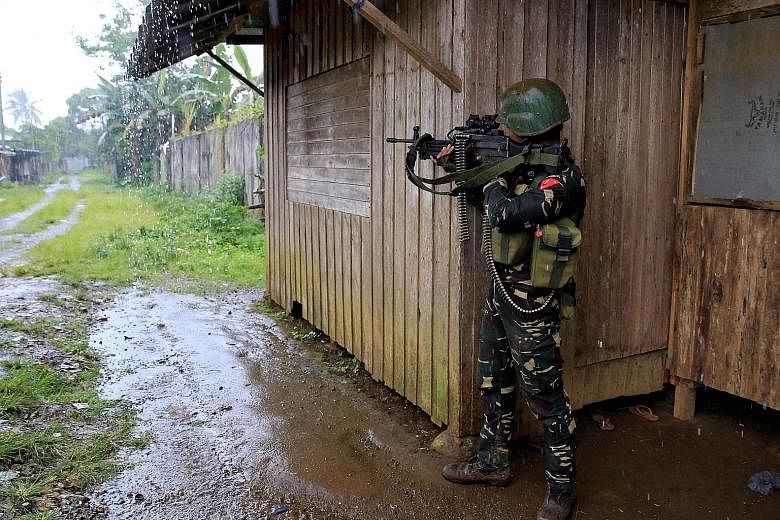 A government soldier yesterday securing an area where residents are said to be trapped in their homes as troops continue their assault on Maute insurgents, who are still holding parts of Marawi City.