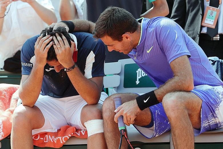 Nicolas Almagro being comforted by Juan Martin del Potro of Argentina after the Spaniard had to quit their French Open second-round match yesterday due to a left-knee injury.
