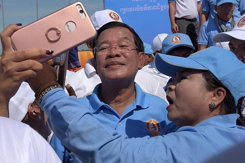 Cambodian Prime Minister Hun Sen posing for photos with supporters of the Cambodian People's Party on the last day of the commune election campaign in Phnom Penh yesterday. The local polls are set to test the mettle of an opposition desperate to upen