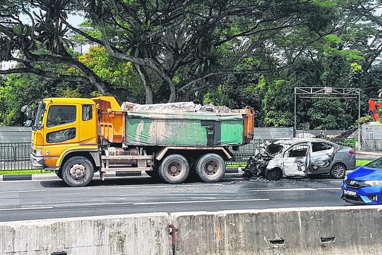 A grey Mitsubishi car in flames near the junction of Clementi Road and Clementi Avenue 2 yesterday afternoon. It is understood that it collided with a tipper truck before bursting into flames.