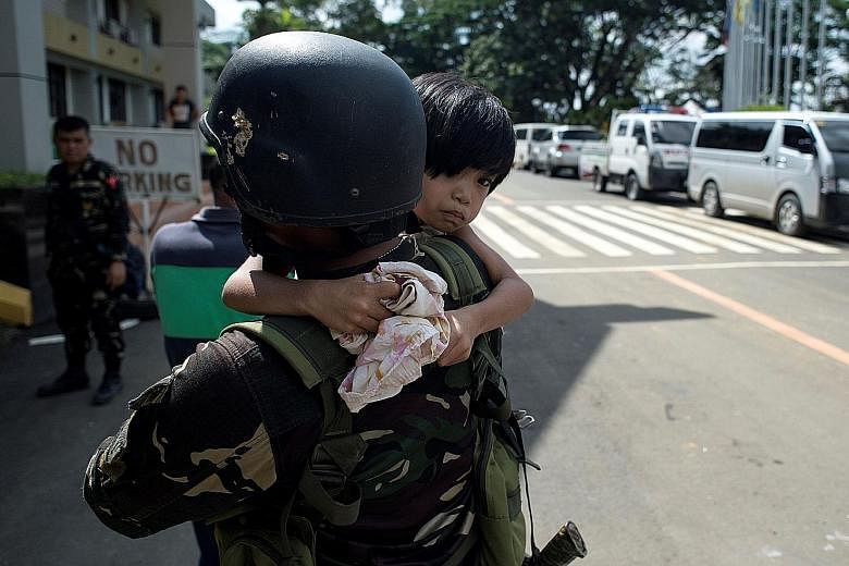 Above: ISIS-influenced suspects being arrested in a Marawi City village yesterday. Below: A soldier carrying a child who was trapped with her family for 11 days at Marawi's Pangarungan Village.