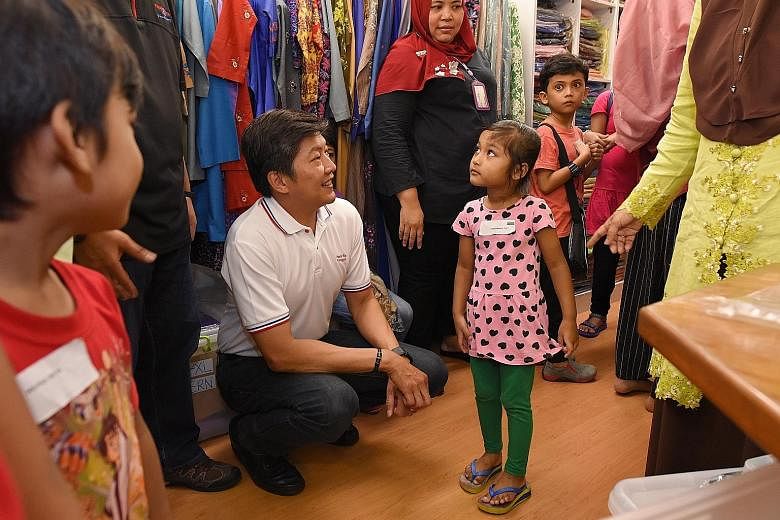 Mr Ng Chee Meng with four-year-old Aliya Natasha at a store in Tanjong Katong Complex. She was among 80 children from low-income families in Punggol North who were taken to the mall for a shopping trip. The children also received new baju kurungs.