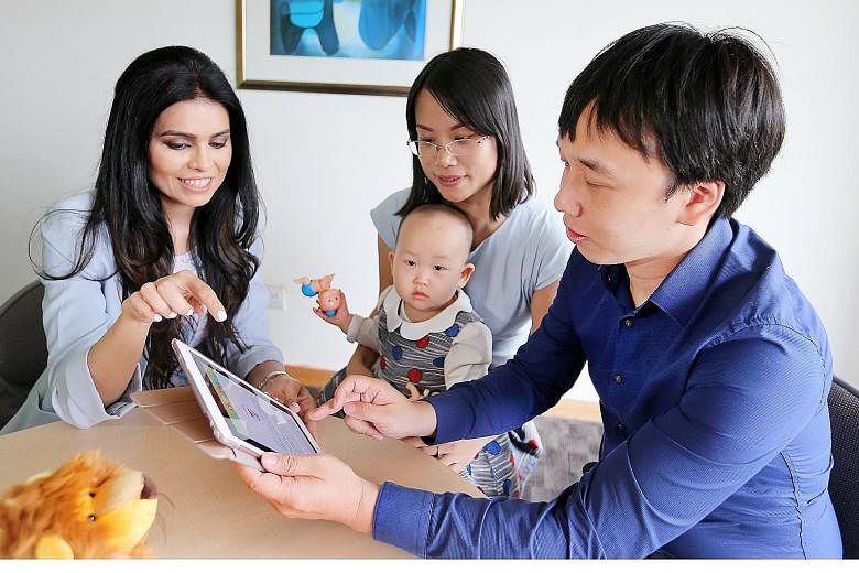 Assistant Professor Shefaly Shorey from NUS' Alice Lee Centre for Nursing Studies showing Mr Zhang Han and his wife, Ms Hu Dan (carrying baby Zhang Mueu), how to retrieve information from the mobile app.