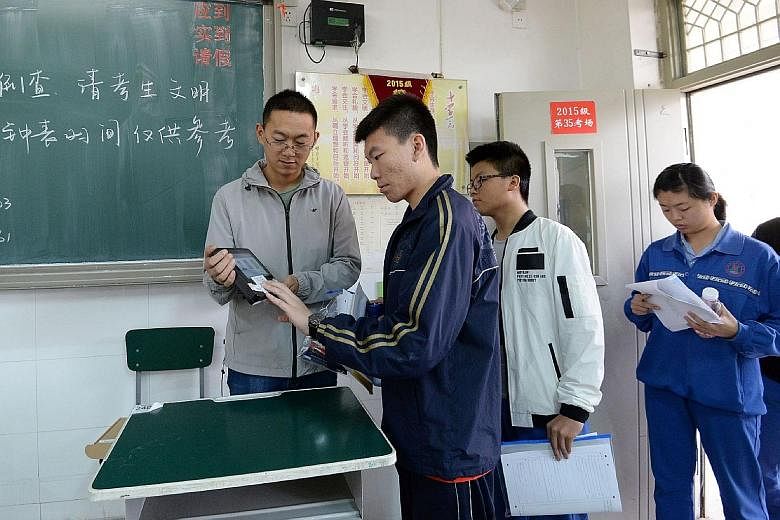 A teacher verifying a student's identity before a simulated gaokao examination in Handan, Hebei province yesterday. Each year, about nine million students take the exams.
