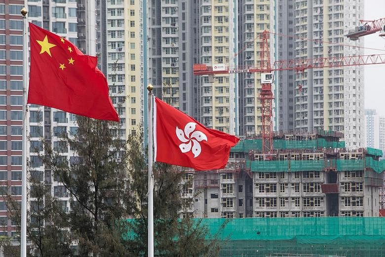 The flags of China (left) and Hong Kong fluttering in front a construction site in Hong Kong. Chinese developers, including HNA and Logan Property, have outbid local contenders for expensive land, snapping up all HK$37 billion (S$6.6 billion) worth 