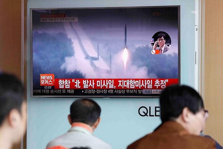 North Korea's launch of land-to-ship missiles being shown on TV at a Seoul railway station.