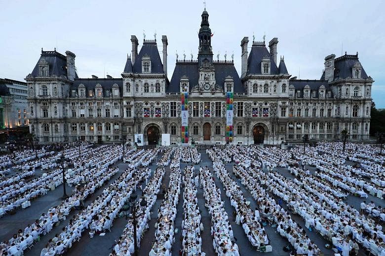 Chic revellers dressed entirely in white taking part in Le Diner en Blanc (Dinner in White) in front of the City Hall in Paris on Thursday. Now into its 29th edition, the annual event draws thousands of guests to each host city around the world, wher
